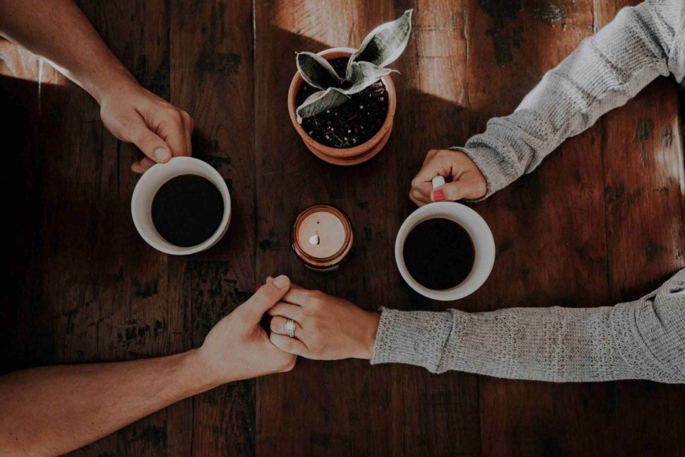 Two people holding hands supportively over a coffee