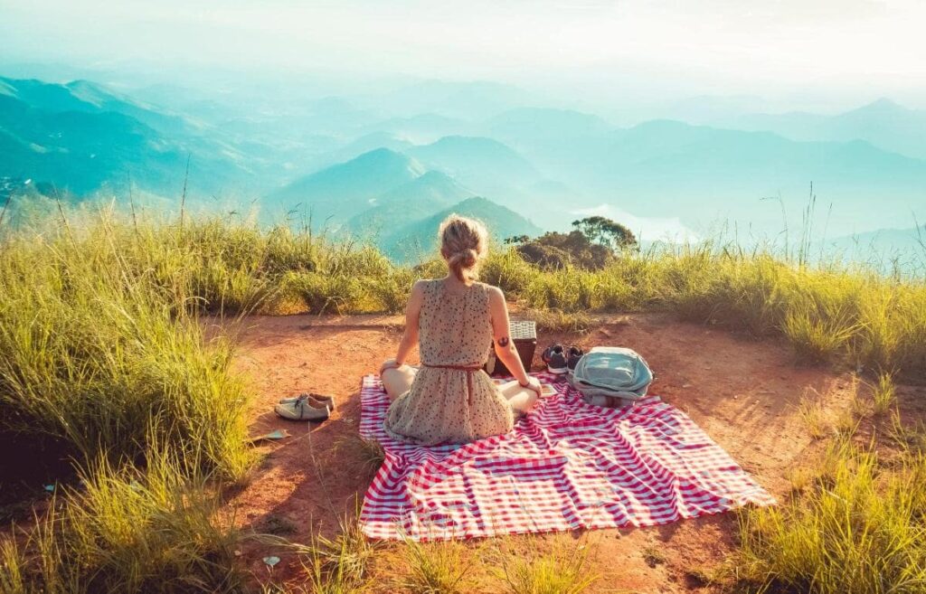 Person sitting on a raised grassy patch of land with views of a valley